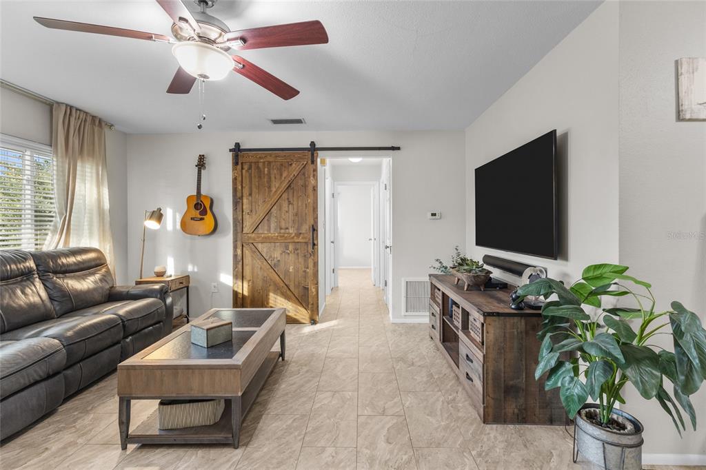 A living room features a leather sofa, a wooden coffee table, and a sliding barn door — 3015 SOUTHERN PARKWAY W, BRADENTON, FL
