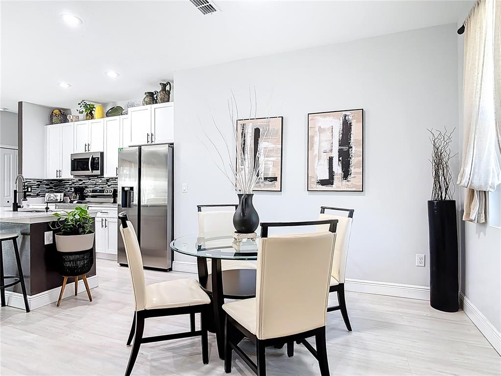 A dining area with a glass-topped table and four chairs sits adjacent to a modern kitchen — 1785 9TH AVENUE, DELAND, FL