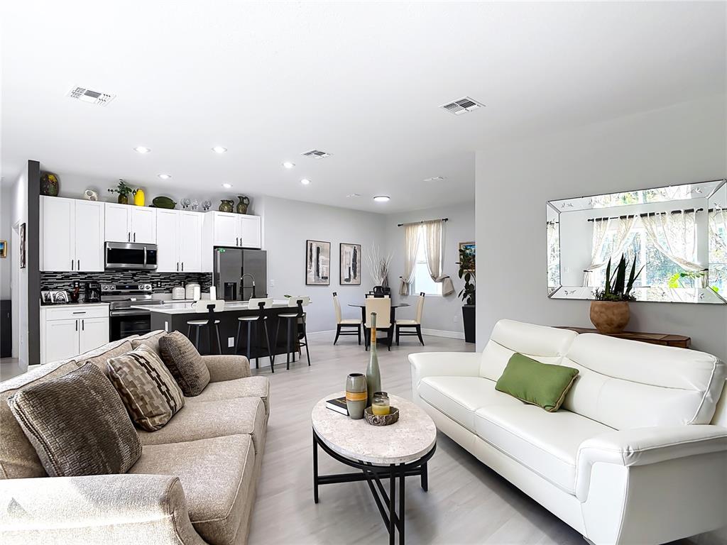 An open-concept living room and kitchen feature white cabinetry, a kitchen island, and two sofas — 1785 9TH AVENUE, DELAND, FL
