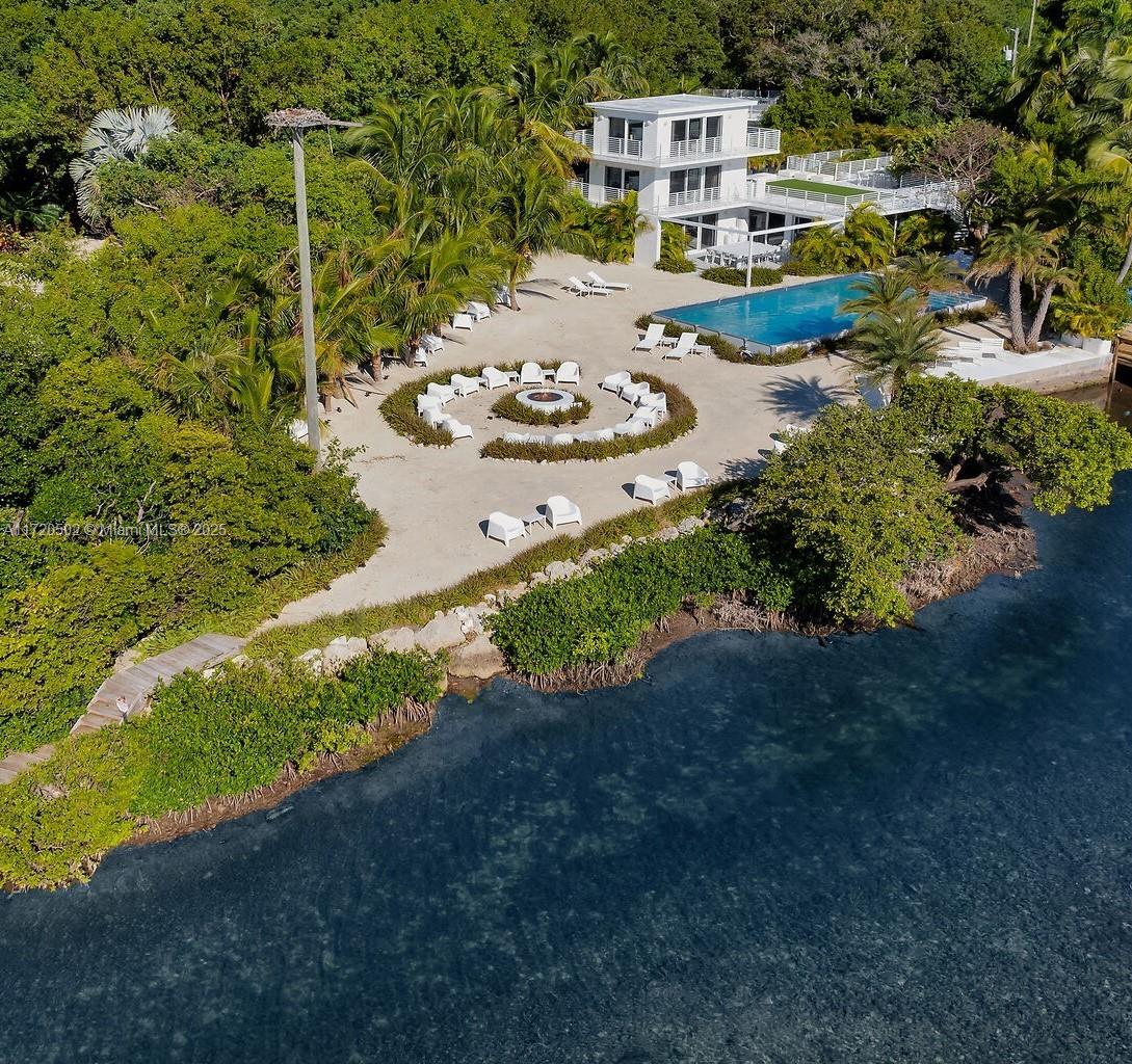 An aerial view shows a modern three-story house with a pool and fire pit area — 98701 Overseas Hwy, Key Largo FL 33037, KEY LARGO, FL
