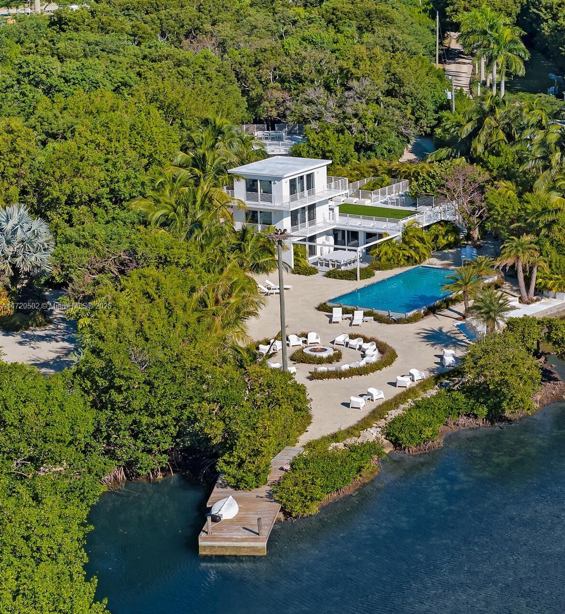 An aerial view of a modern three-story house with a pool, patio, and private dock — 98701 Overseas Hwy, Key Largo FL 33037, KEY LARGO, FL