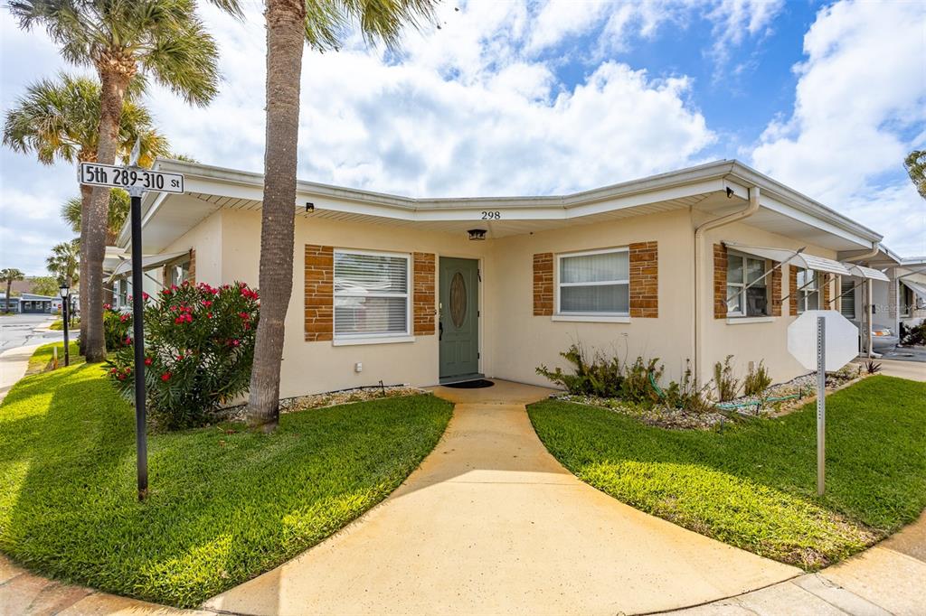 A single-story house with a beige exterior, a green front door, and a palm tree — 250 ROSERY ROAD NW UNIT 298, LARGO, FL