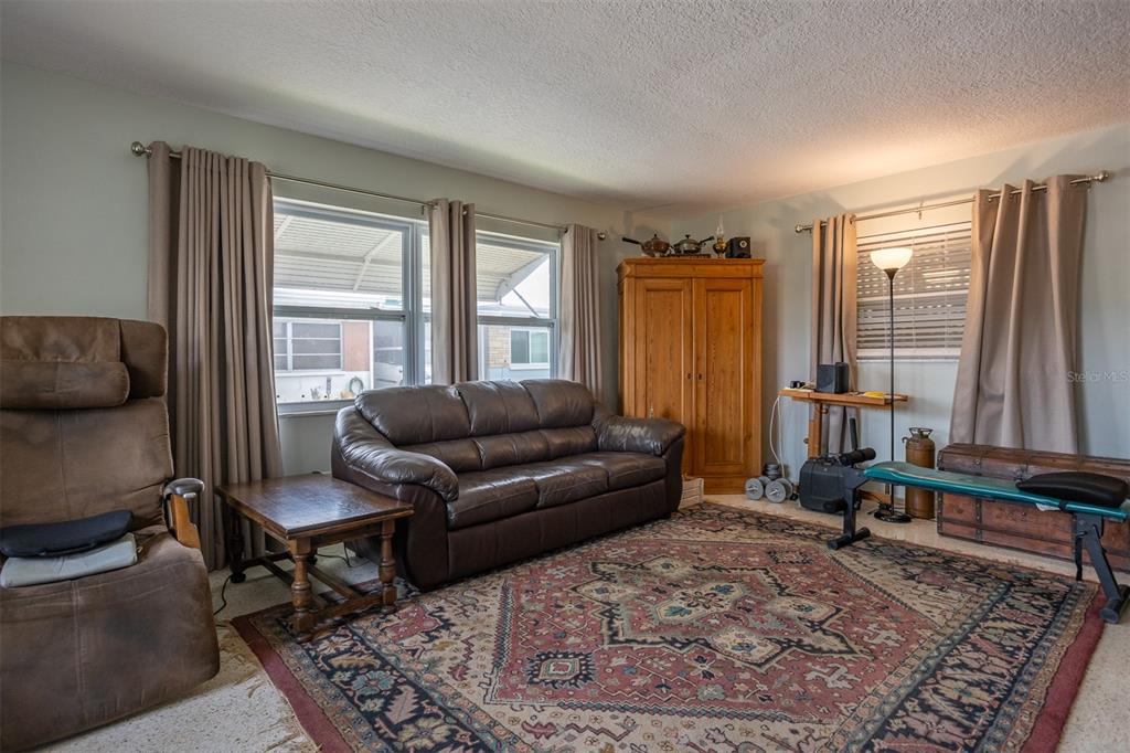 A living room features a brown leather sofa, a recliner, and a patterned area rug — 250 ROSERY ROAD NW UNIT 298, LARGO, FL
