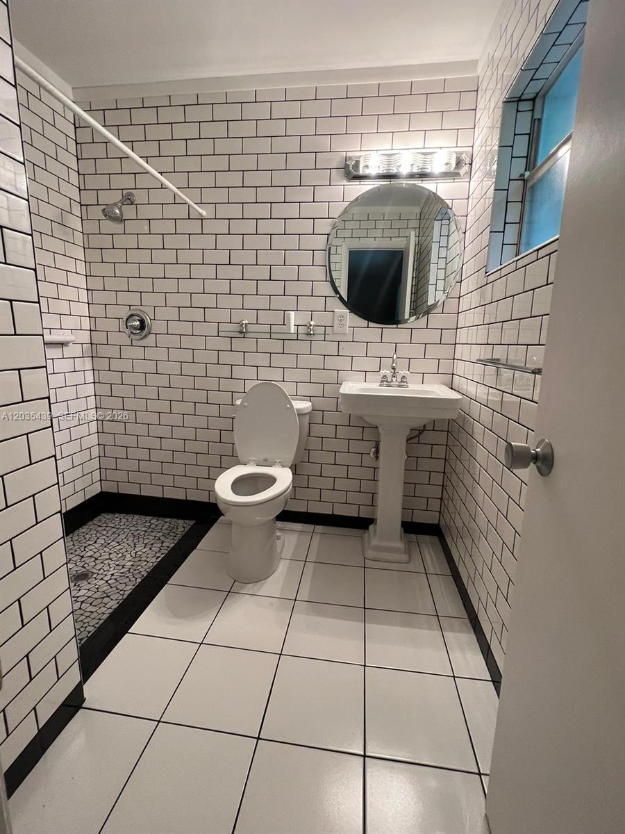 A bathroom features white subway tile walls, a pedestal sink, a toilet, and a shower — 2916 12th Ave, Vero Beach FL 32960, VERO BEACH, FL