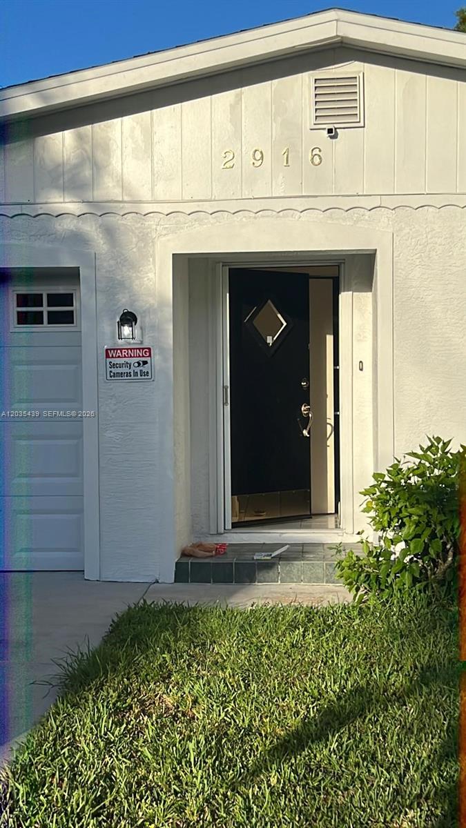 A white house exterior features a black front door, a security sign, and a garage — 2916 12th Ave, Vero Beach FL 32960, VERO BEACH, FL