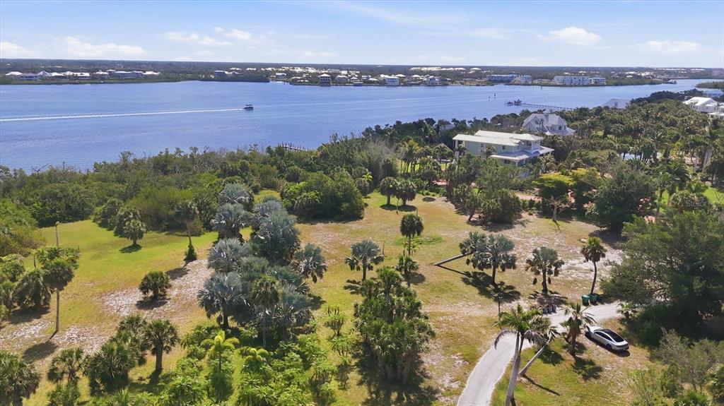 An aerial view shows a large, grassy lot with palm trees near a wide river — 10450 SUNNY DREAMS TERRACE, PLACIDA, FL