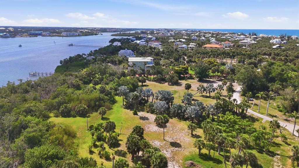 An aerial view shows a coastal property with lush vegetation, palm trees, and a waterfront home — 10450 SUNNY DREAMS TERRACE, PLACIDA, FL