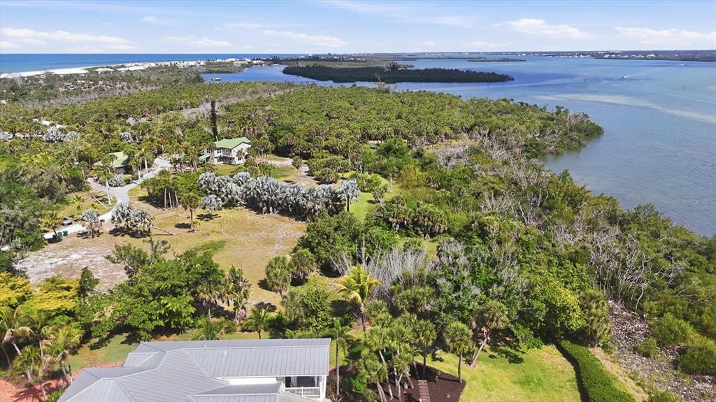 An aerial view shows a coastal property with a house, dense vegetation, and waterfront access — 10450 SUNNY DREAMS TERRACE, PLACIDA, FL
