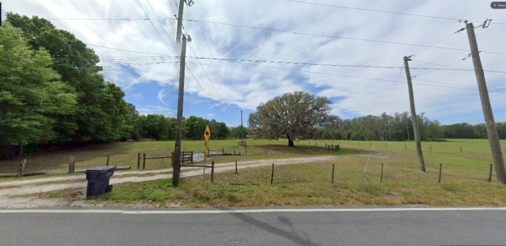 A gravel driveway leads to a large, grassy field with a prominent oak tree — GREEN POND RD, POLK CITY, FL