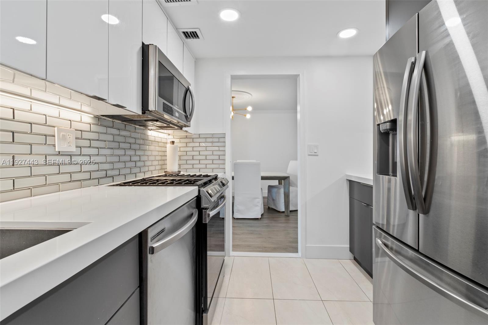 A modern kitchen features white cabinets, stainless steel appliances, and a subway tile backsplash — 3140 S Ocean Dr # 511, Hallandale Beach FL 33009, HALLANDALE BEACH, FL