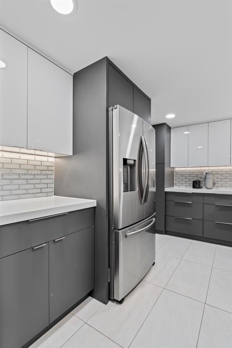 A modern kitchen features gray lower cabinets, white upper cabinets, and stainless steel appliances — 3140 S Ocean Dr # 511, Hallandale Beach FL 33009, HALLANDALE BEACH, FL