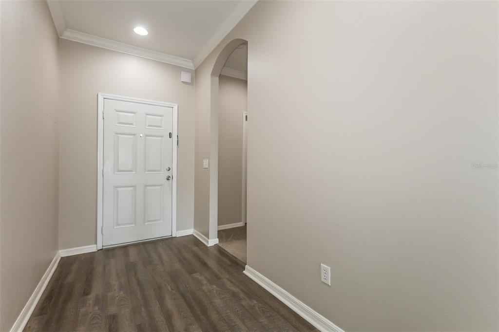 An entryway features wood-look flooring, a white front door, and an arched doorway — 814 COADE STONE DRIVE, SEFFNER, FL