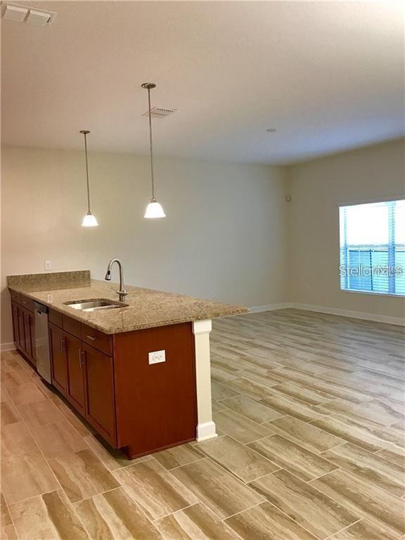 A kitchen island with granite countertops and pendant lighting sits in an open-concept room — 1599 MOON VALLEY DRIVE, DAVENPORT, FL