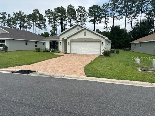 A single-story house with a paved driveway and a two-car garage sits on a grassy lot — 7673 SW 180TH CIRCLE, DUNNELLON, FL