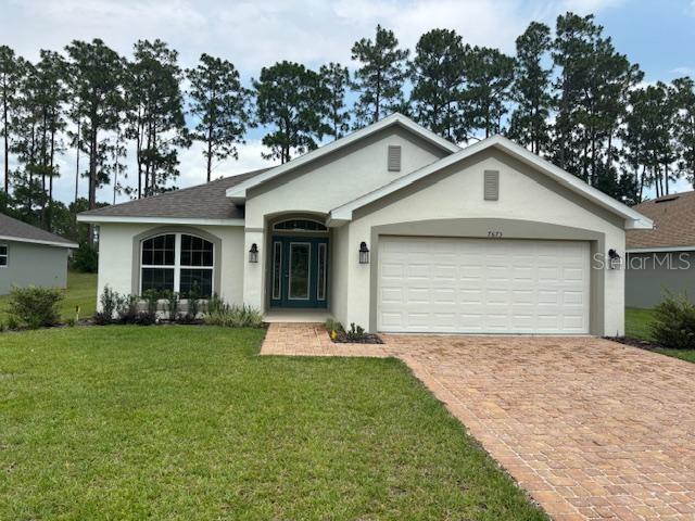 A single-story house with a beige stucco exterior, a two-car garage, and a brick driveway — 7673 SW 180TH CIRCLE, DUNNELLON, FL
