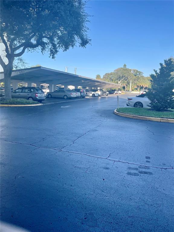A parking lot with covered carports and several parked vehicles under a clear blue sky — 1224 S PENINSULA DRIVE UNIT 304, DAYTONA BEACH, FL