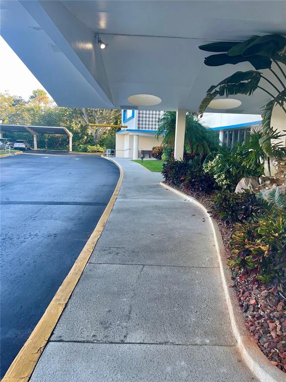 A concrete walkway leads under a covered entrance beside a parking lot and landscaping — 1224 S PENINSULA DRIVE UNIT 304, DAYTONA BEACH, FL