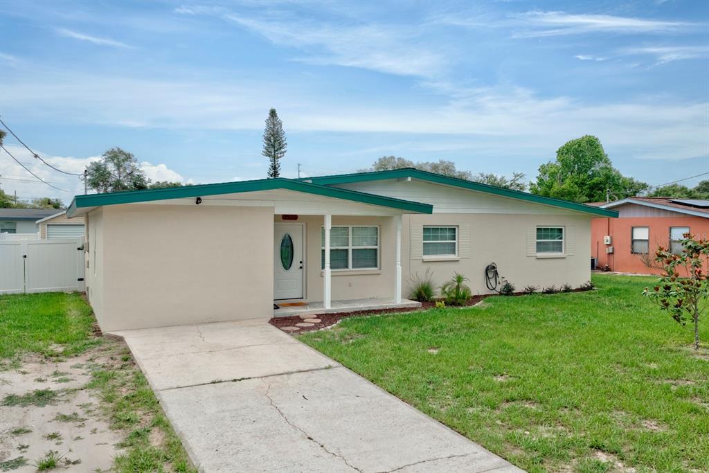 A single-story house with a beige exterior, green trim, and a concrete driveway — 2326 CLEVELAND ROAD, SEBRING, FL