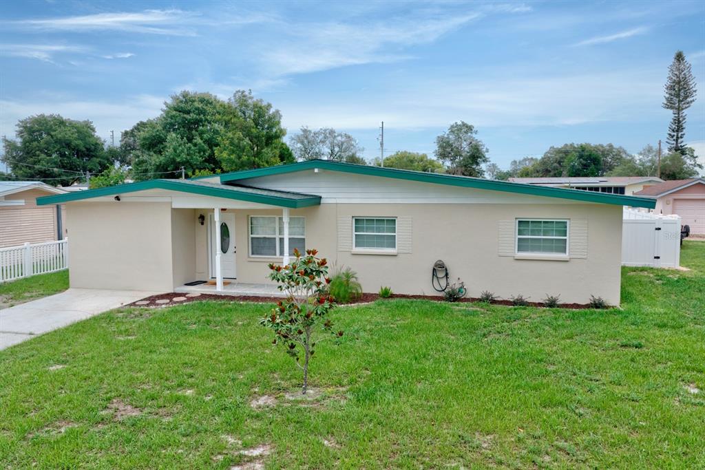 A single-story house with beige stucco siding, a green roof, and a small front yard — 2326 CLEVELAND ROAD, SEBRING, FL