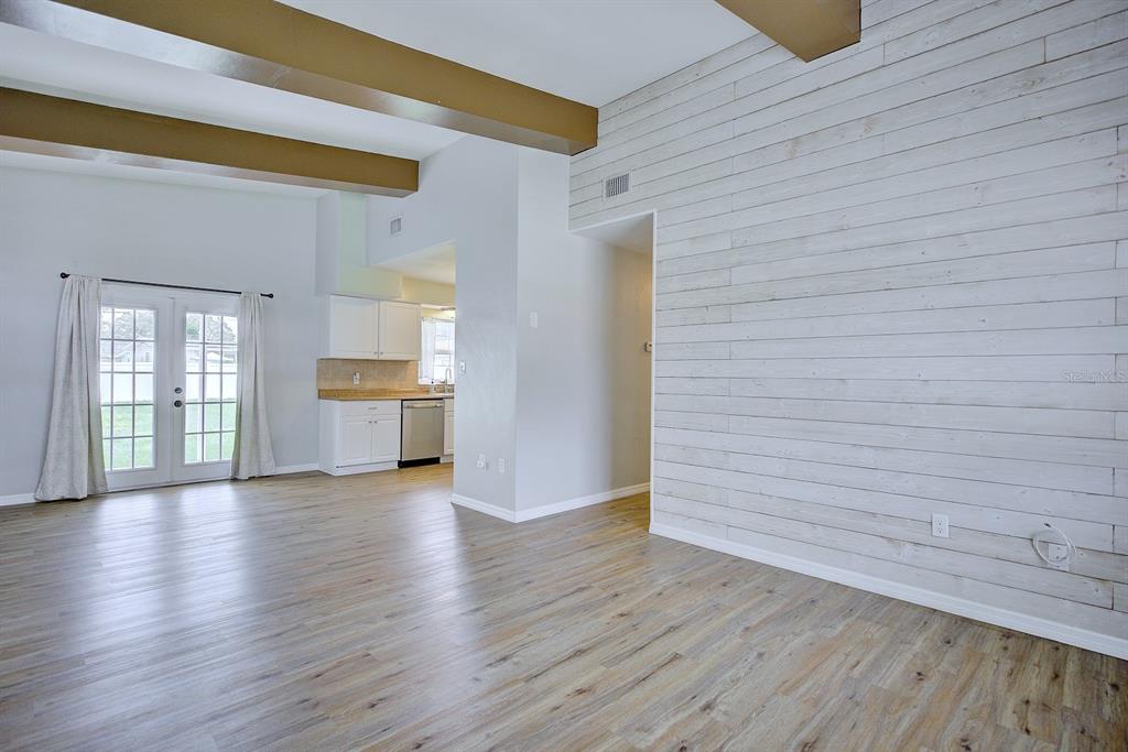 A living room features wood-look flooring, exposed ceiling beams, and a white shiplap accent wall — 2326 CLEVELAND ROAD, SEBRING, FL