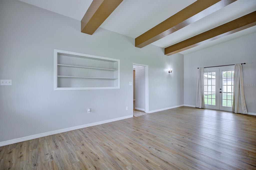 A living room features light gray walls, wood-look flooring, exposed ceiling beams, and built-in shelving — 2326 CLEVELAND ROAD, SEBRING, FL