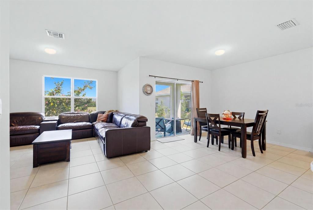 A living and dining area with tile flooring, a leather sectional, and sliding glass doors — 258 RIO DE JANEIRO AVENUE, PUNTA GORDA, FL