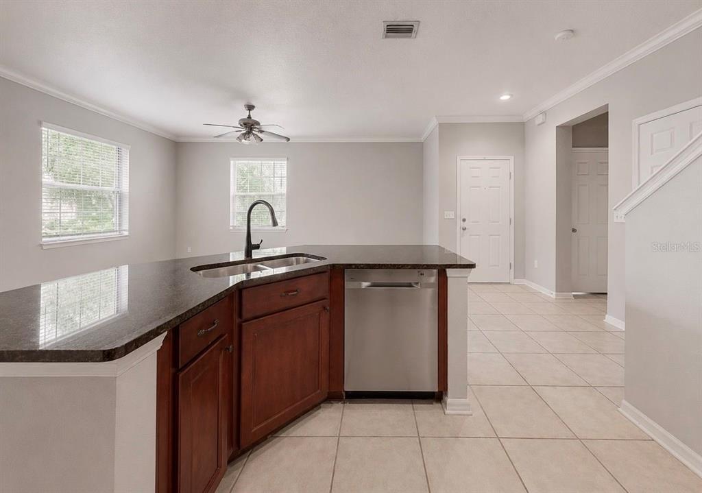 A kitchen features dark wood cabinets, granite countertops, stainless steel appliances, and tile flooring — 7539 TAMARIND AVENUE, TAMPA, FL