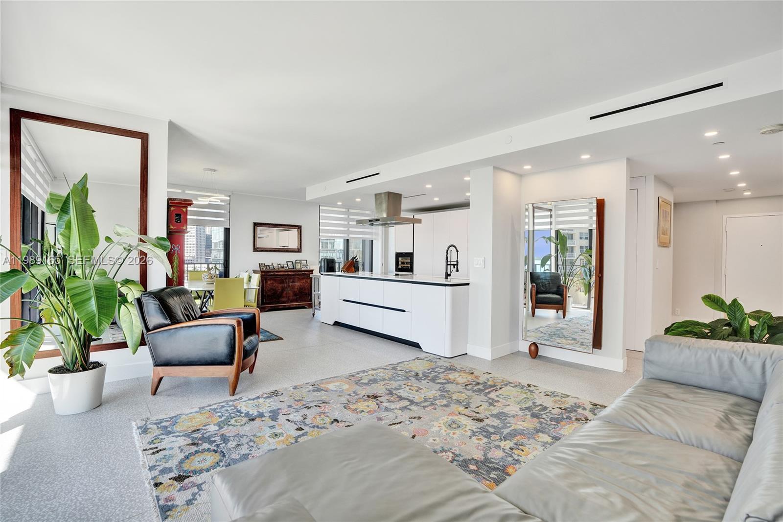 A modern open-concept living room and kitchen featuring a large island and area rug — 520 Brickell Key Dr # A1015, Miami FL 33131, MIAMI, FL