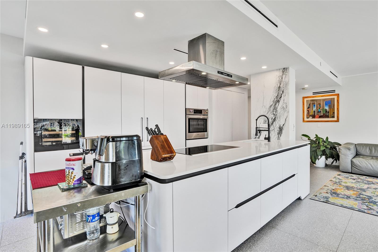 A modern kitchen features white cabinetry, a large island with a cooktop, and stainless appliances — 520 Brickell Key Dr # A1015, Miami FL 33131, MIAMI, FL