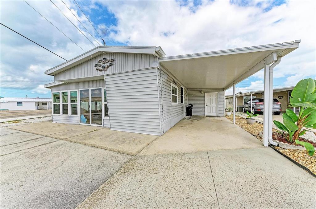 A light gray mobile home with a concrete driveway, attached carport, and sliding glass doors — 6626 TEXAS STREET, BRADENTON, FL