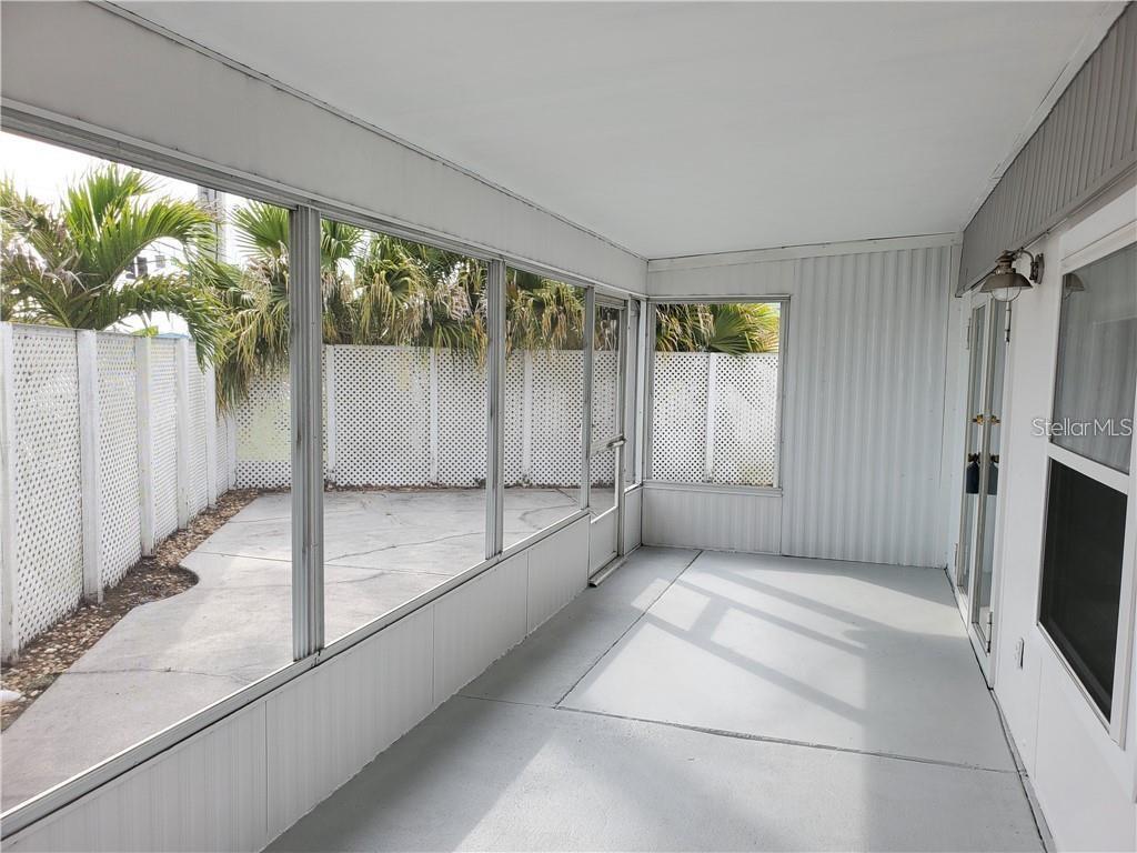 A screened-in porch features gray painted flooring, white walls, and a view of a patio — 6626 TEXAS STREET, BRADENTON, FL
