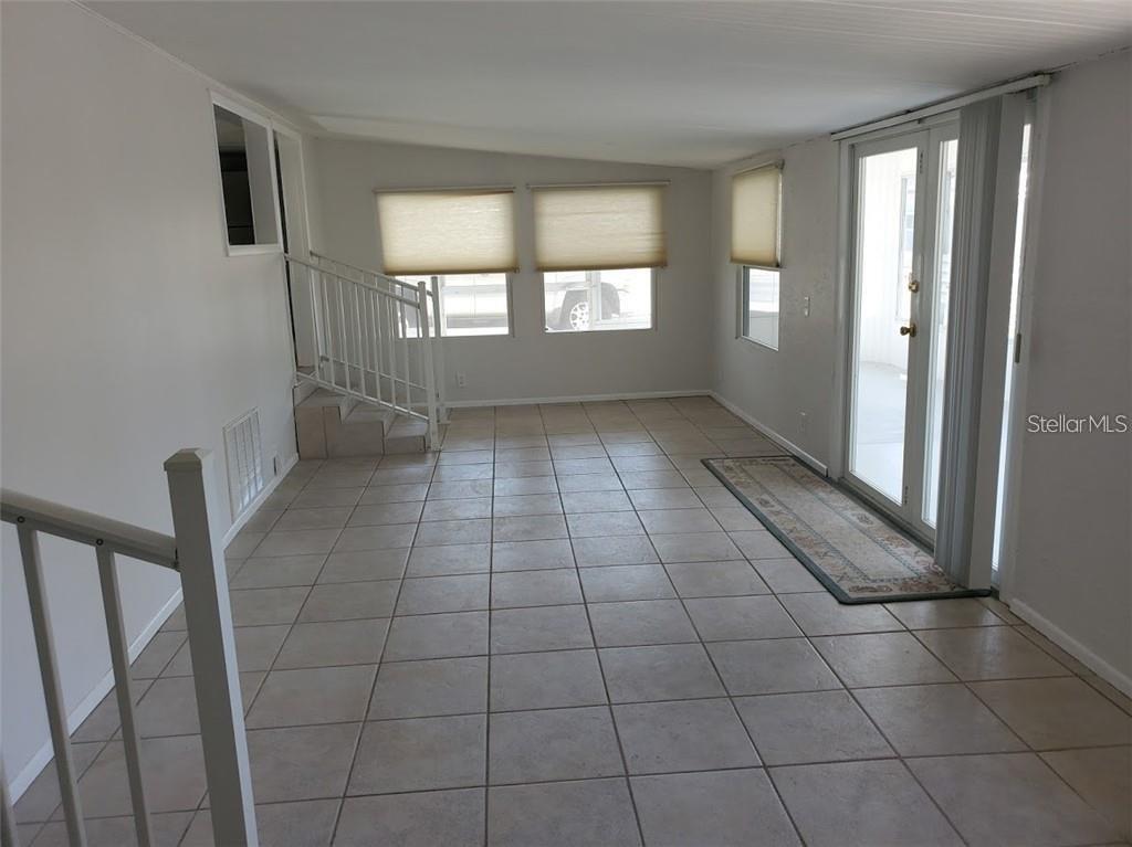 A sunroom with light-colored tile flooring, a white staircase, and glass doors leading outside — 6626 TEXAS STREET, BRADENTON, FL
