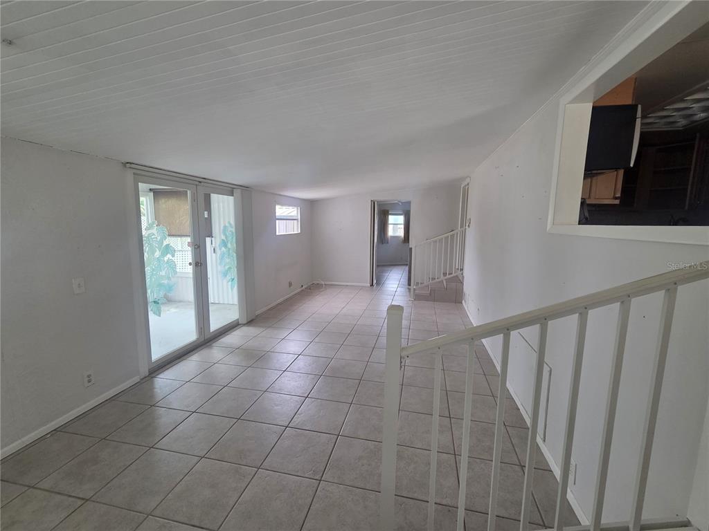 A bright room features white walls, tiled floors, a staircase, and sliding glass doors — 6626 TEXAS STREET, BRADENTON, FL