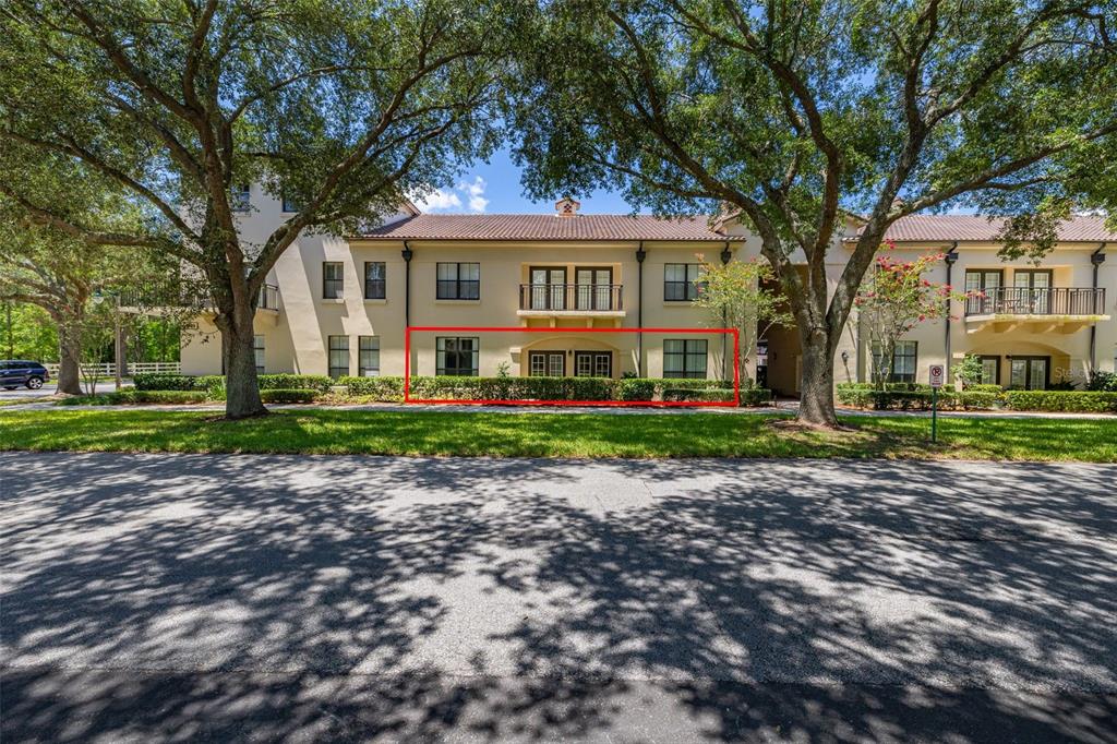A two-story apartment building exterior with a red-outlined ground floor unit and mature trees — 949 WESTPARK DRIVE UNIT 106, KISSIMMEE, FL