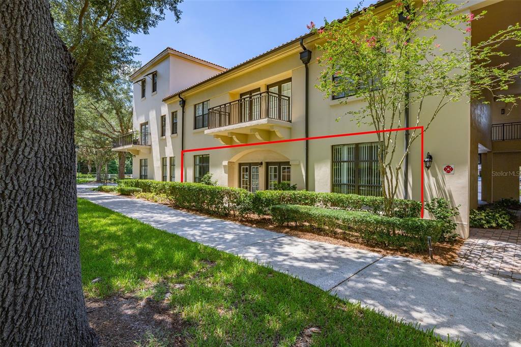 The exterior of a multi-story building features a ground-floor patio area with glass doors — 949 WESTPARK DRIVE UNIT 106, KISSIMMEE, FL
