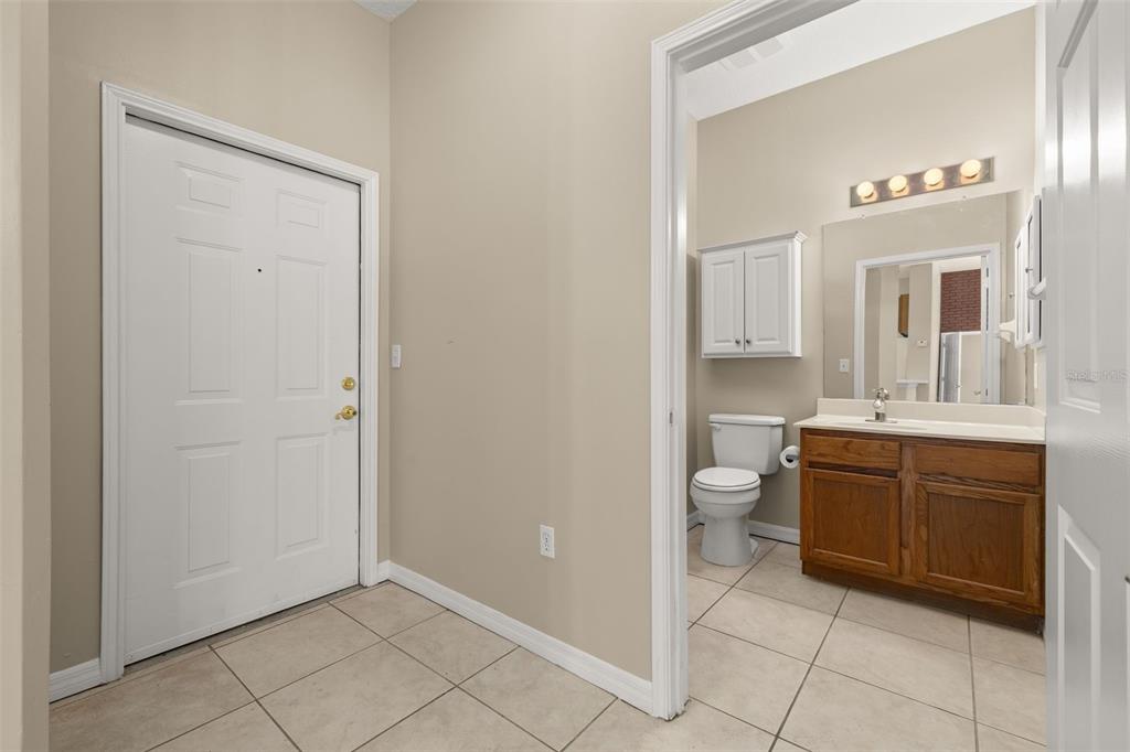 A tiled entryway leads to a bathroom featuring a wooden vanity and a white toilet — 949 WESTPARK DRIVE UNIT 106, KISSIMMEE, FL