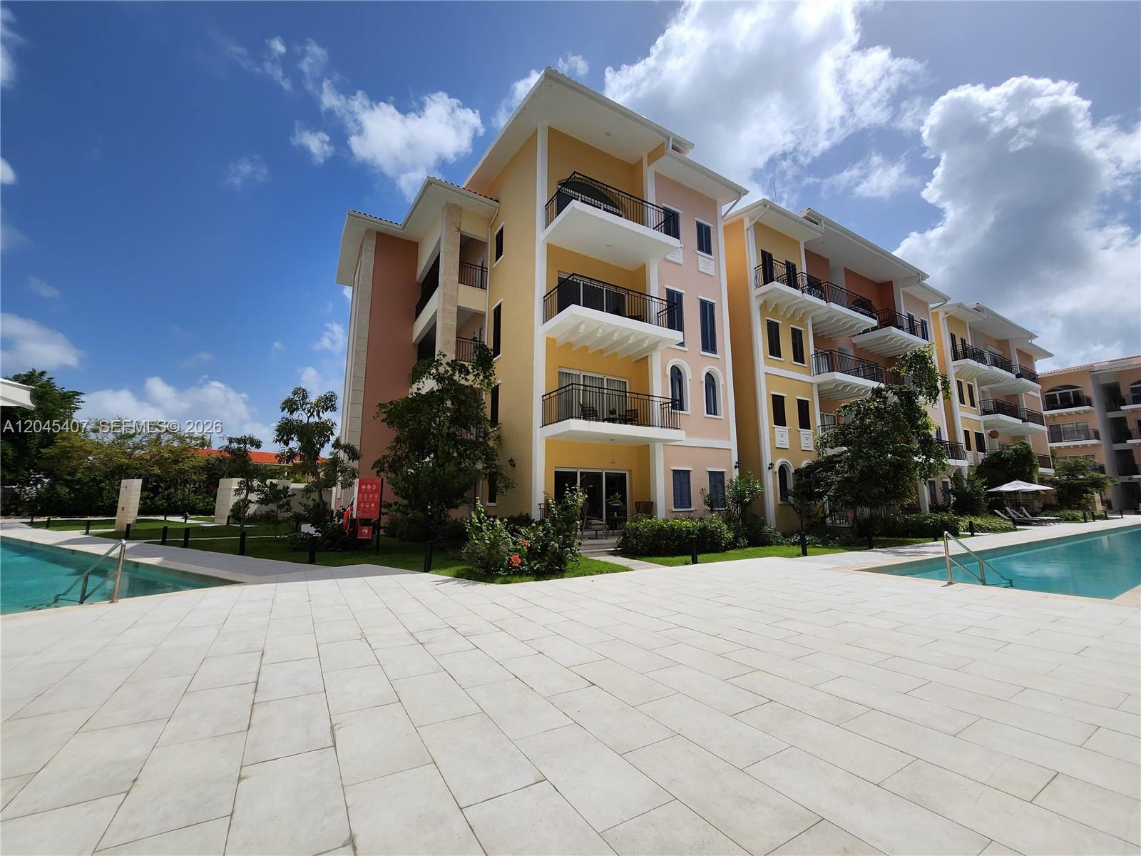A multi-story apartment building with balconies overlooks a swimming pool and paved patio area — D.R. AVENIDA ALEMANIA # 2, DR, DR