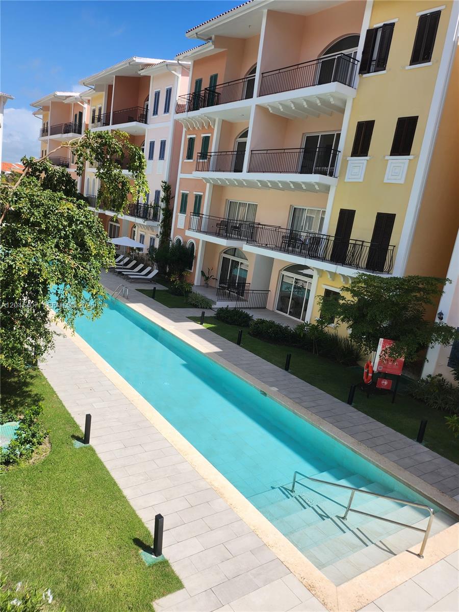 A long, narrow swimming pool sits alongside a multi-story apartment building with balconies — D.R. AVENIDA ALEMANIA # 2, DR, DR