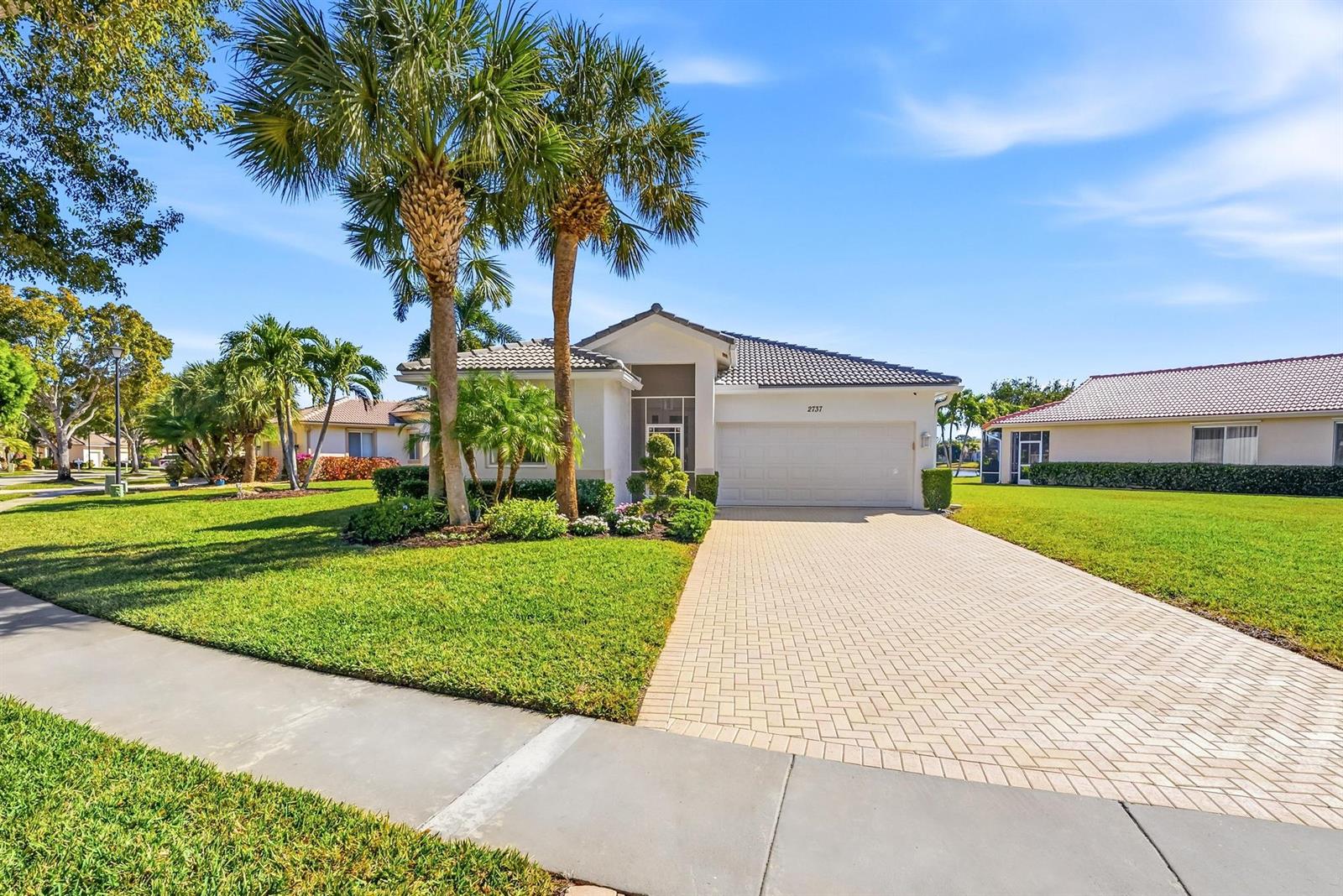 A single-story house with a paved driveway, palm trees, and a tiled roof — 2737 Clipper Circle, West Palm Beach FL 33411, WEST PALM BEACH, FL