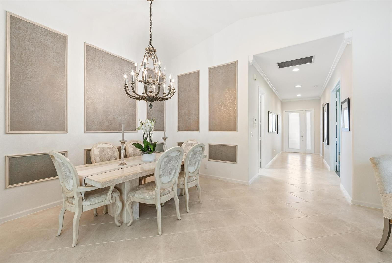 A formal dining room features a chandelier, a stone table, and decorative wall panels — 2737 Clipper Circle, West Palm Beach FL 33411, WEST PALM BEACH, FL