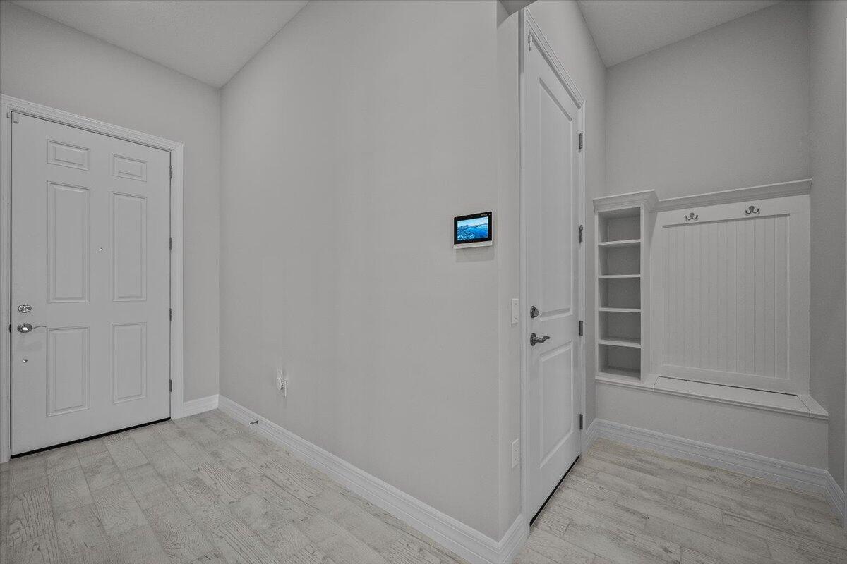 An entryway features light wood-look tile flooring, a white door, and a built-in mudroom bench — 10366 Northbrook Circle, Palm Beach Gardens FL 33412, PALM BEACH GARDENS, FL