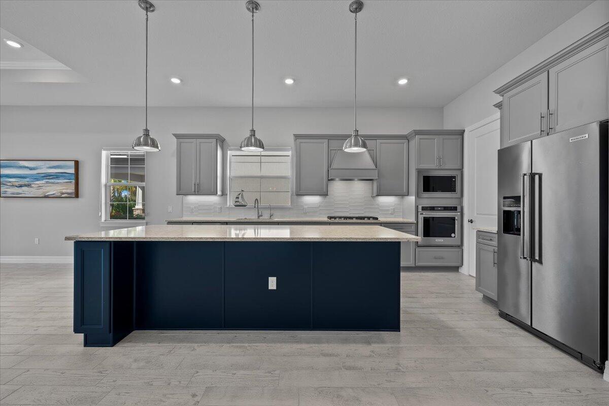 A kitchen features a dark blue island, grey cabinetry, stainless steel appliances, and light flooring — 10366 Northbrook Circle, Palm Beach Gardens FL 33412, PALM BEACH GARDENS, FL