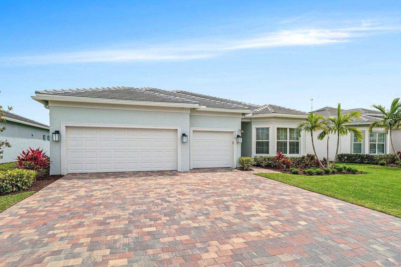 A single-story house with a three-car garage and a paved driveway under a blue sky — 9578 Mosler Trail, Lake Worth FL 33467, LAKE WORTH, FL