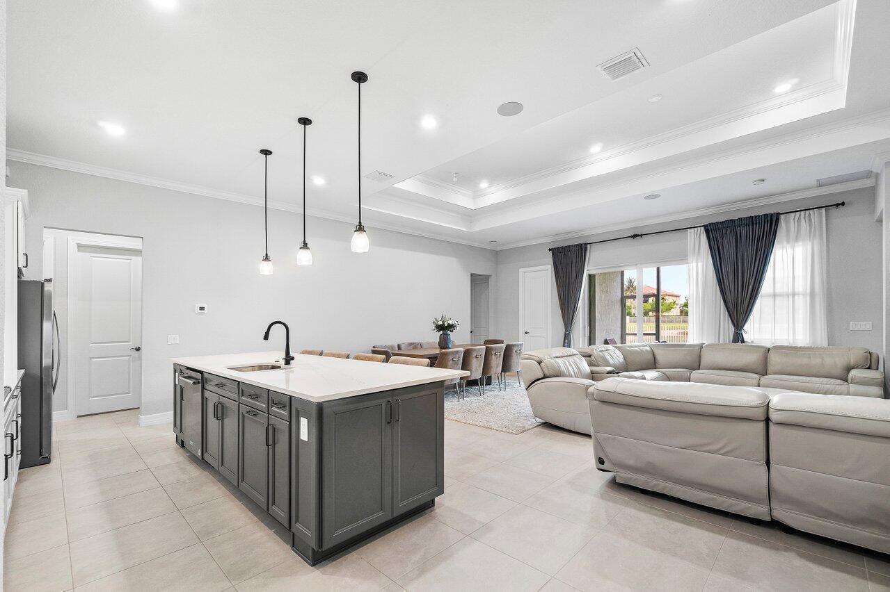 A modern open-concept kitchen and living area featuring a large gray island and sectional sofa — 9578 Mosler Trail, Lake Worth FL 33467, LAKE WORTH, FL
