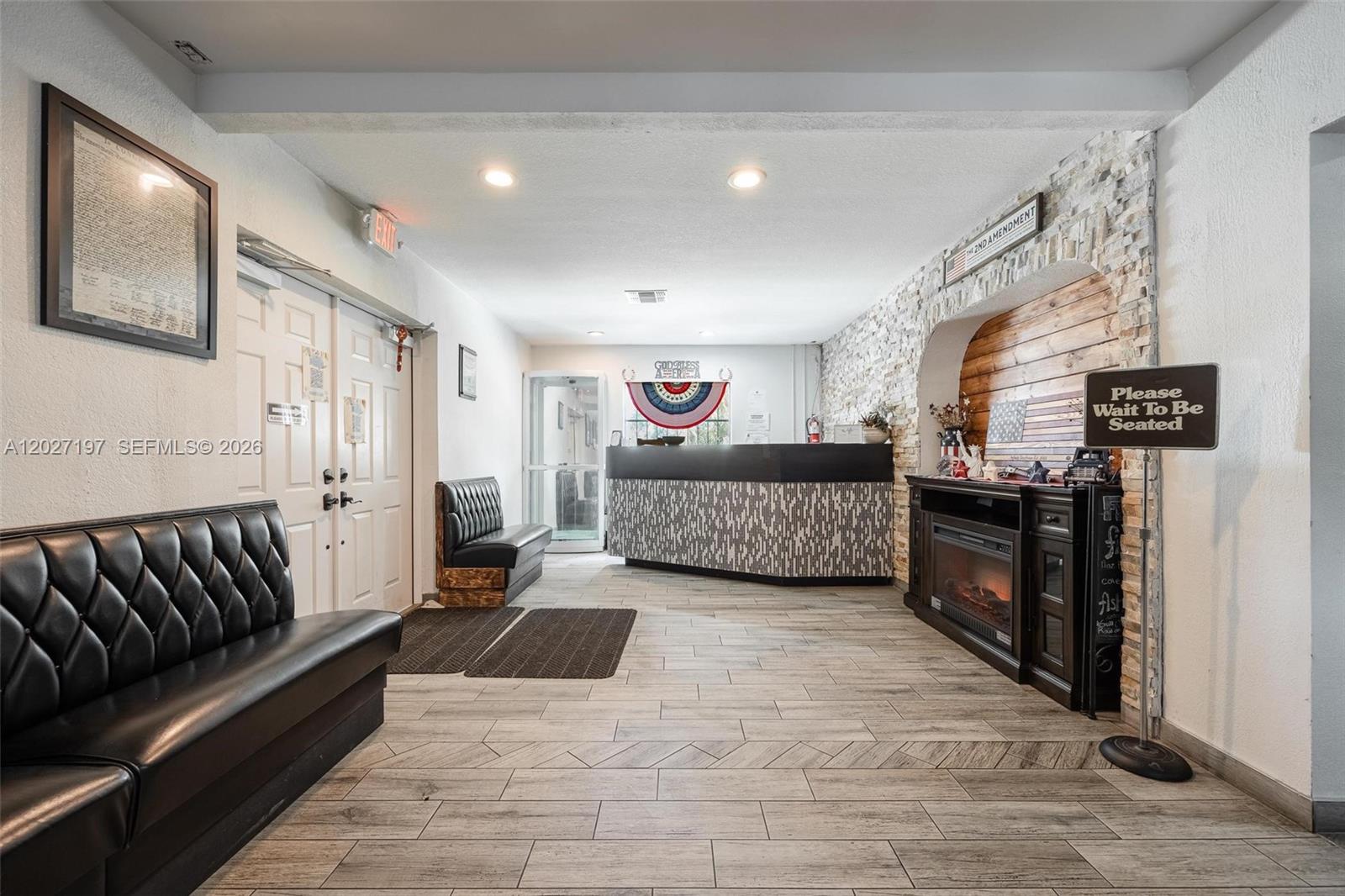 A waiting area features a reception desk, black leather benches, and a stone-accented fireplace — 93 S Hall ST, La Belle FL 33935, LA BELLE, FL