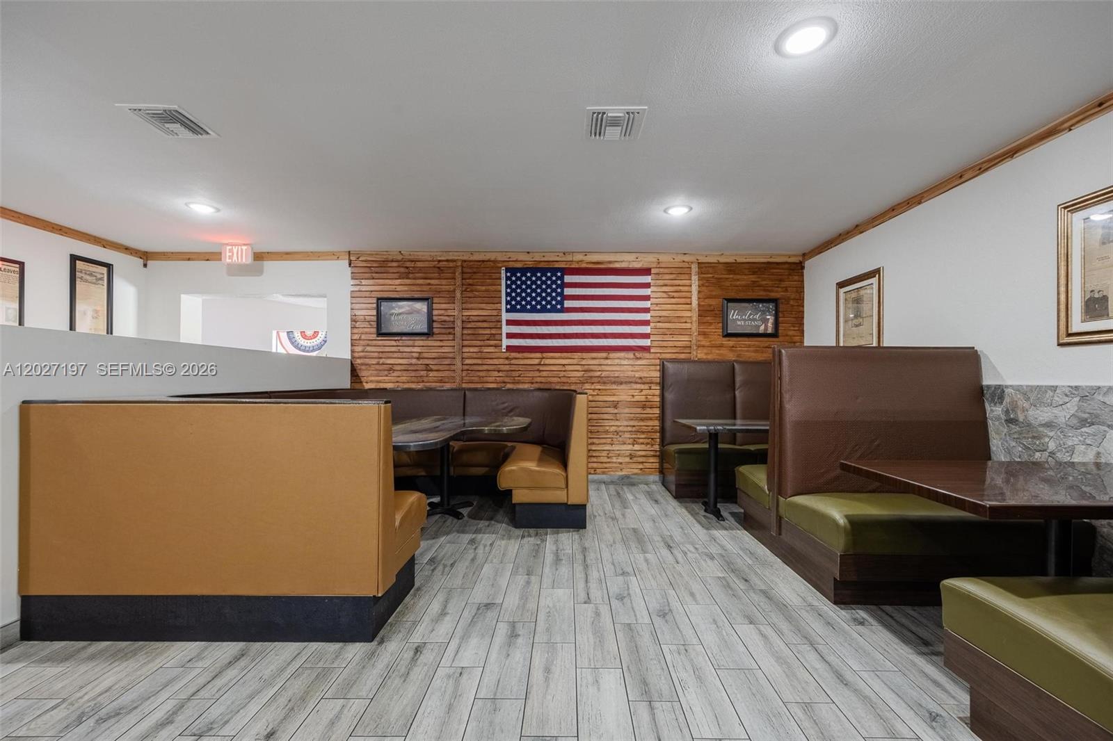 A restaurant dining area features multiple booths, wood-paneled walls, an American flag, and wood-look flooring — 93 S Hall ST, La Belle FL 33935, LA BELLE, FL