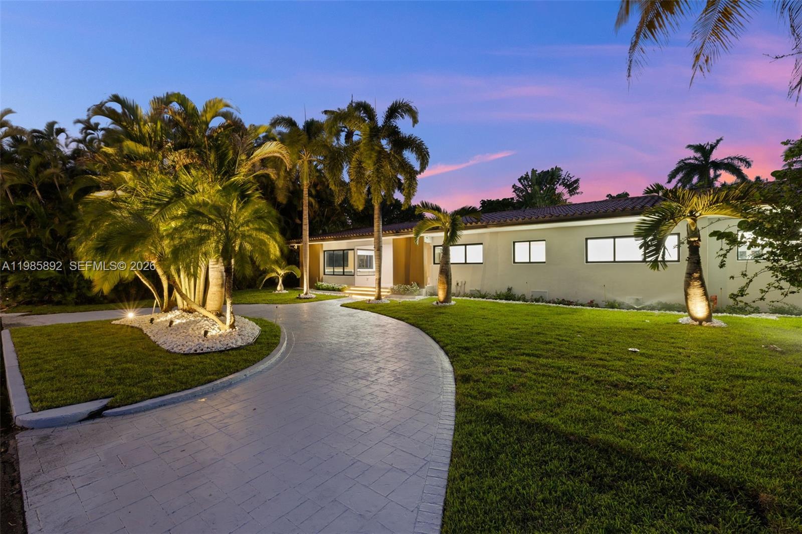 A single-story house with a curved paved driveway and palm trees at dusk — 1117 Adams st, Hollywood FL 33019, HOLLYWOOD, FL