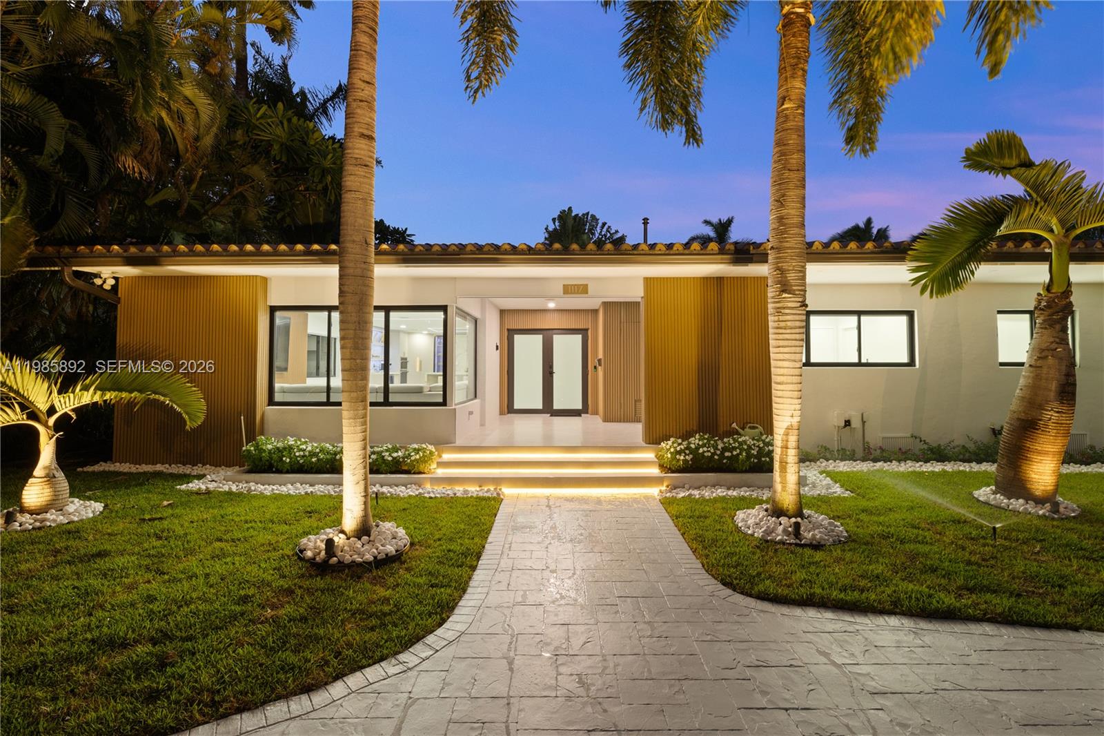 The exterior of a single-story house features a paved walkway, palm trees, and illuminated steps — 1117 Adams st, Hollywood FL 33019, HOLLYWOOD, FL