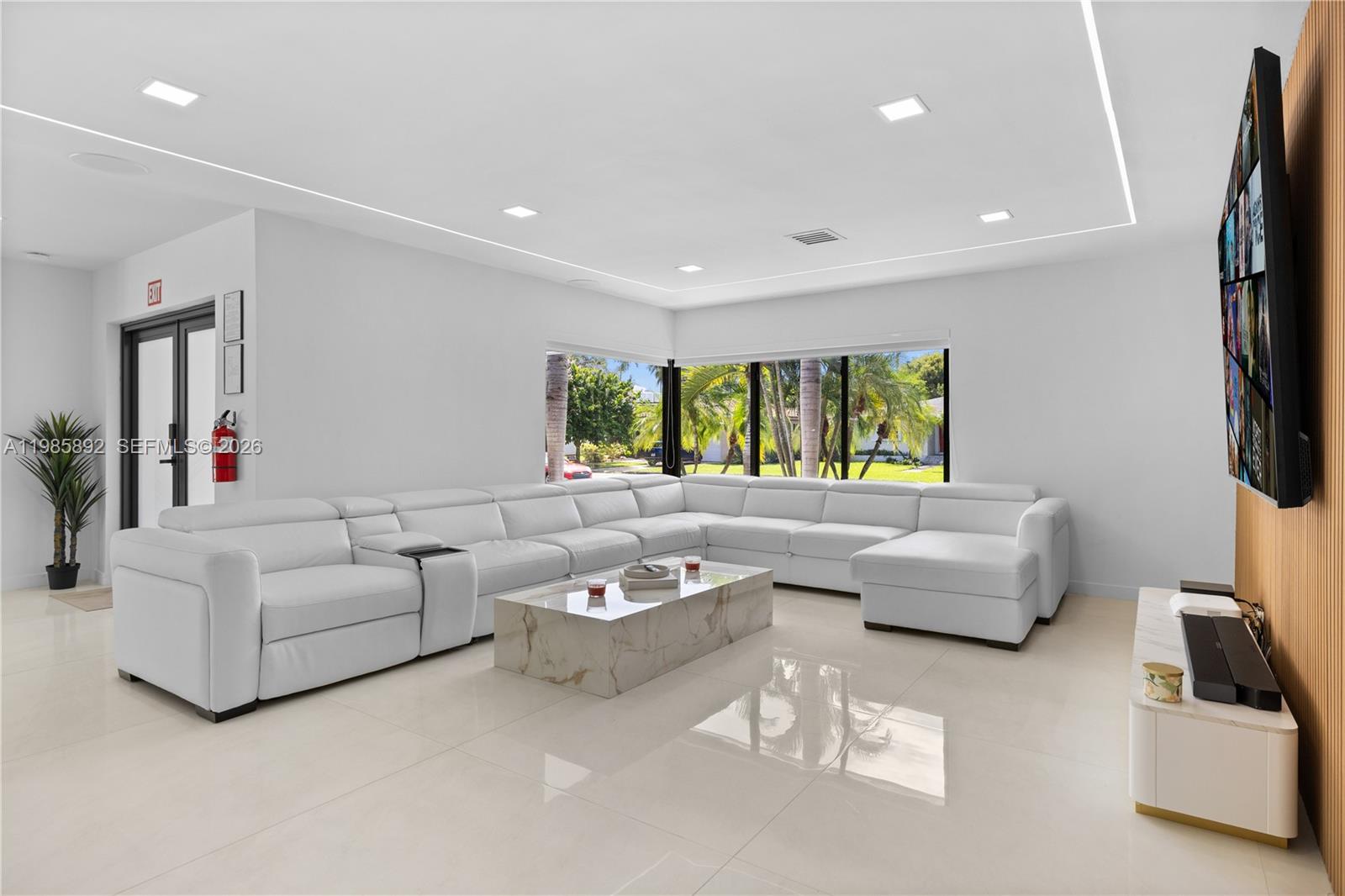 A modern living room features a large white sectional sofa, marble coffee table, and wall-mounted television — 1117 Adams st, Hollywood FL 33019, HOLLYWOOD, FL