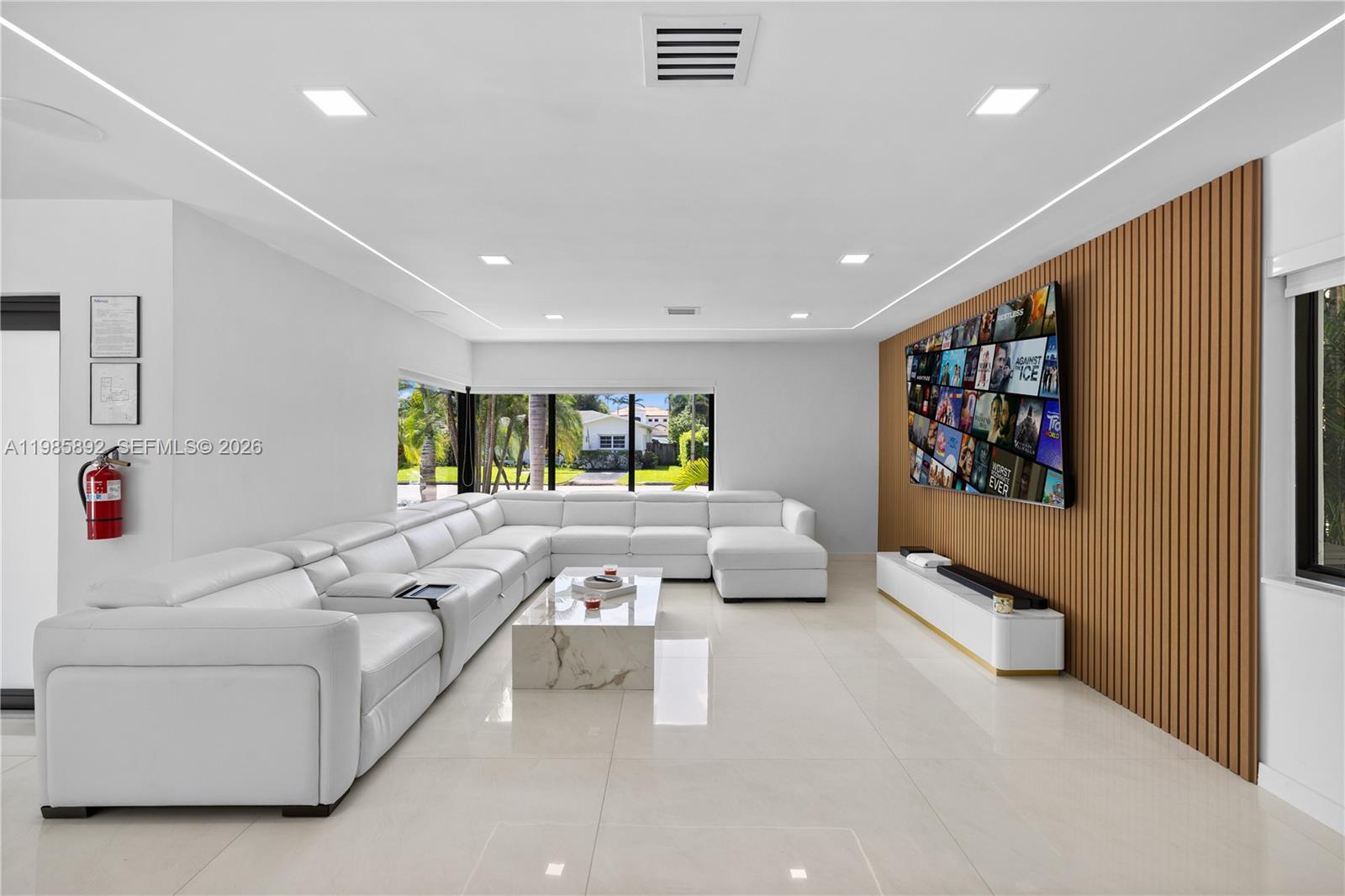 A modern living room features a white sectional sofa, marble coffee table, and wood-slatted wall — 1117 Adams st, Hollywood FL 33019, HOLLYWOOD, FL